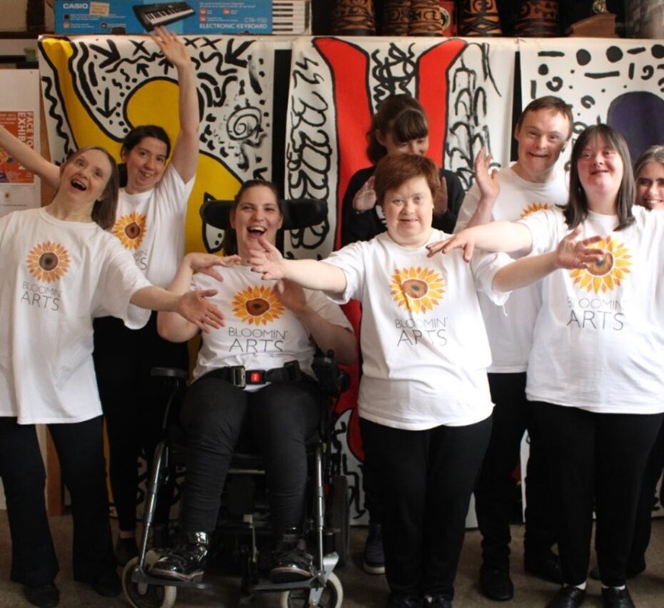 group of disabled adults with hands outstretched and laughing after a dance performance.