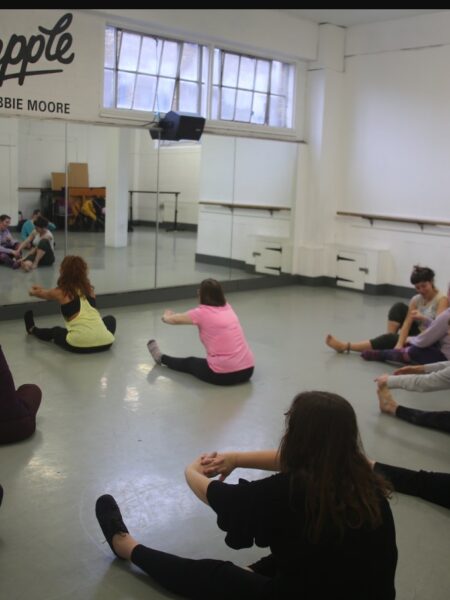 dancers sat on floor doing stretches.