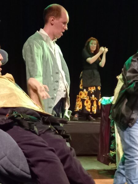 3 men in theatre show, one speaking - sign language interpreter in background