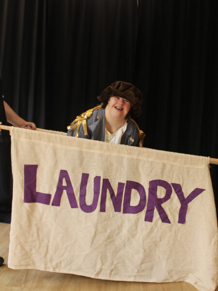 An actor with a hat on behind a screen saying laundry